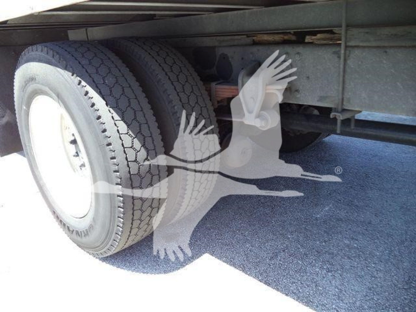 Truck rear dual tires and undercarriage with suspension and frame visible.