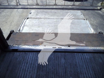 Truck bed with liftgate gap showing flat aluminum platform and metal step, viewed from rear cargo area.