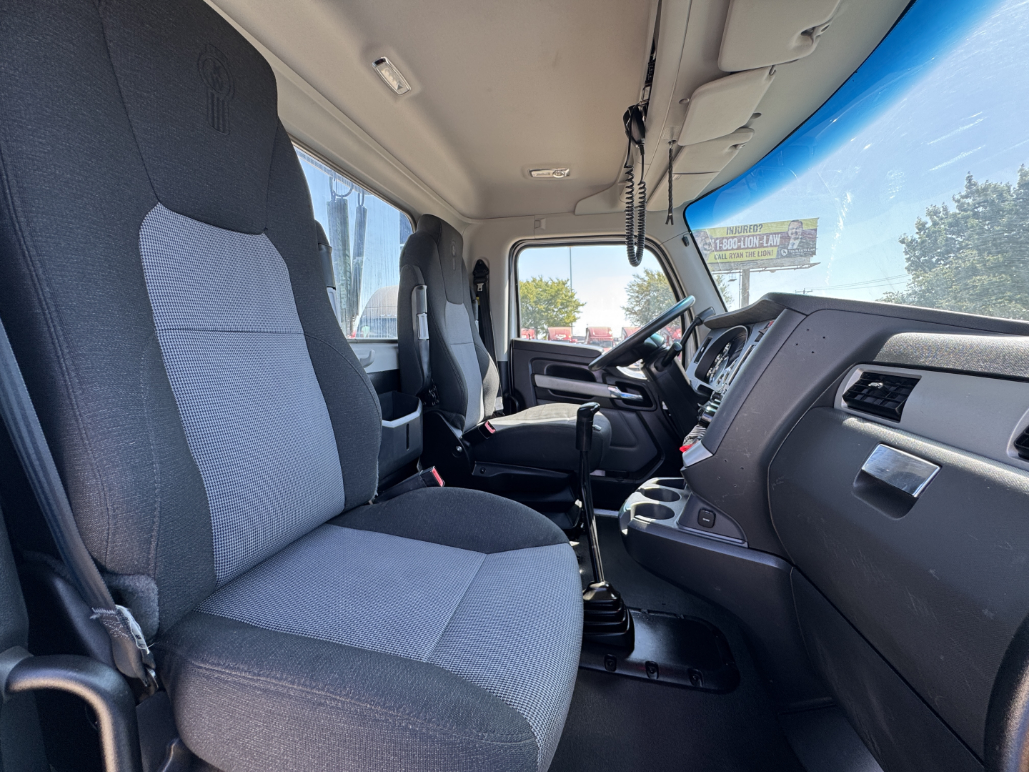 Kenworth T680 cab interior showing driver and passenger seats, steering wheel, dashboard, gear lever, and center console.