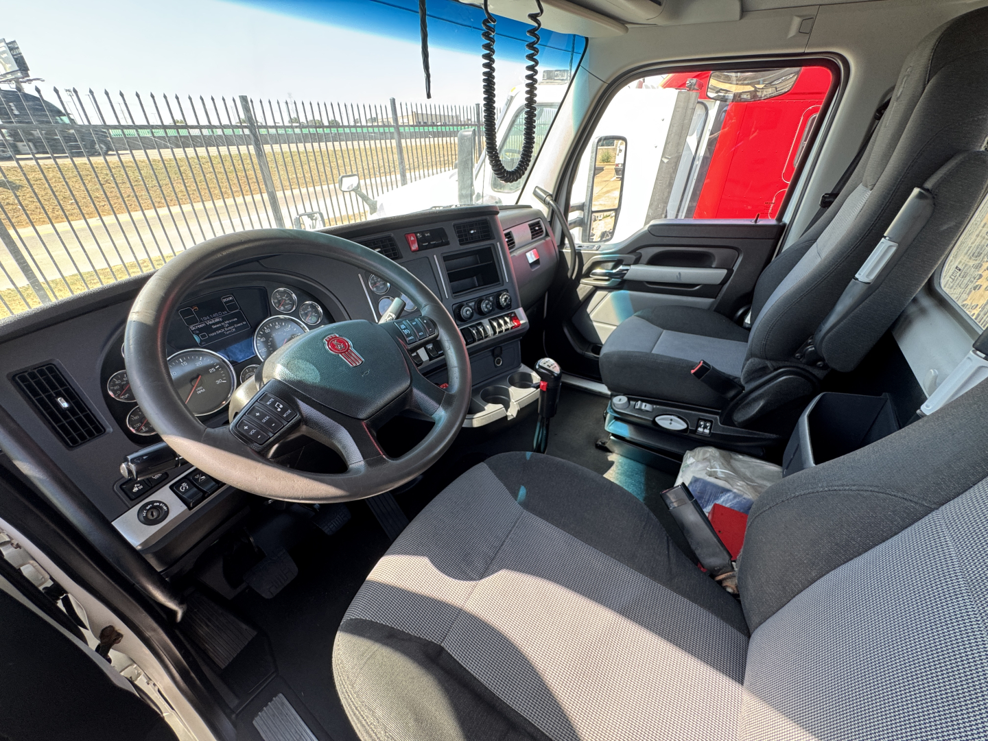 Kenworth T680 interior showing steering wheel, dashboard, front seats, and center console.