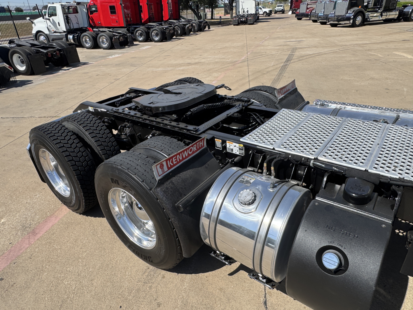 Kenworth truck rear chassis showing fuel tanks and dual rear axles, with Kenworth badge near fuel tank and aluminum catwalk.