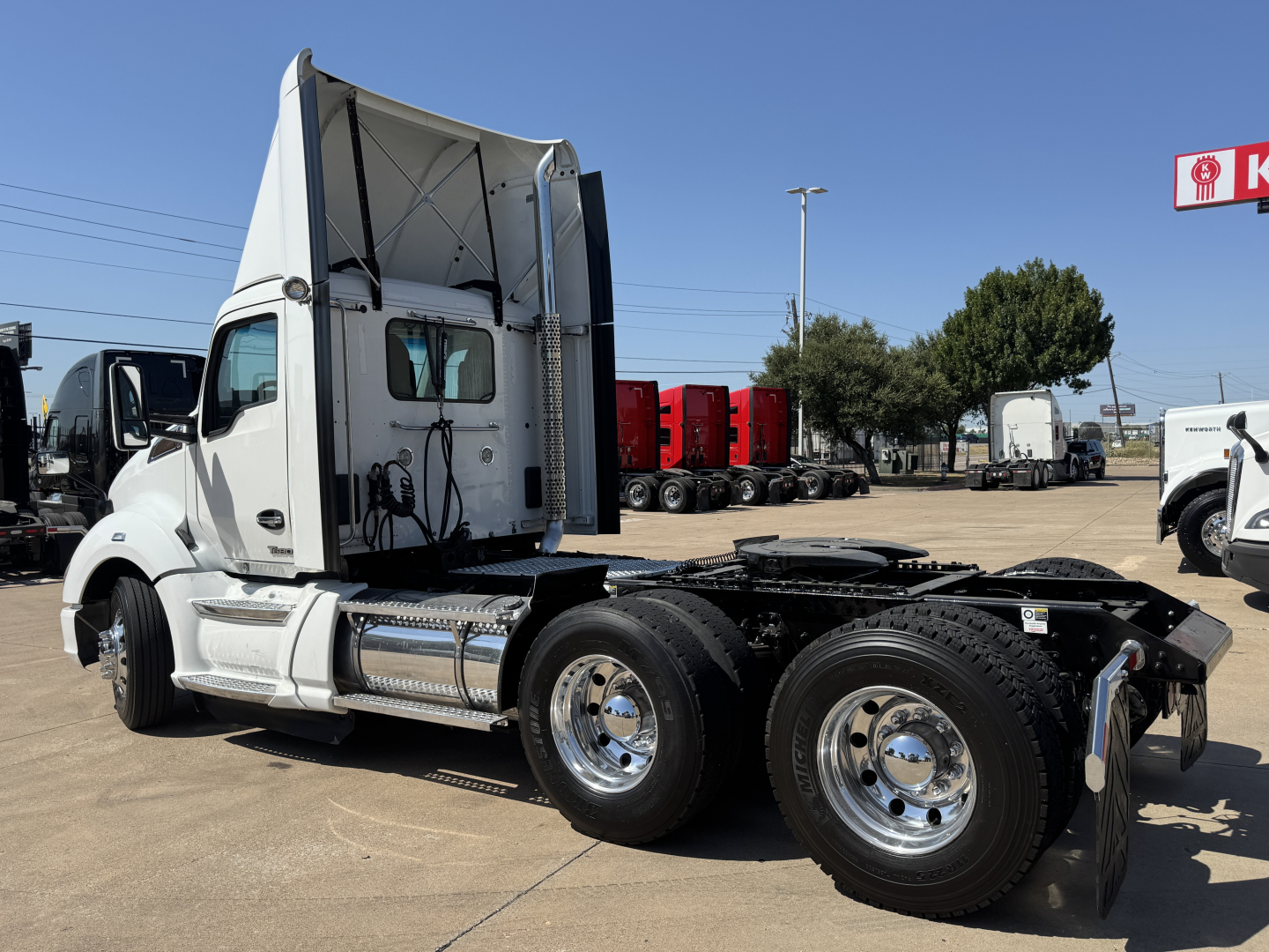 Kenworth T680 concrete day cab tractor with extended sleeper cabin, single sleeper, dual rear axles and chrome fuel tanks. Side view showing chassis, wheels, and fifth wheel mounting.
