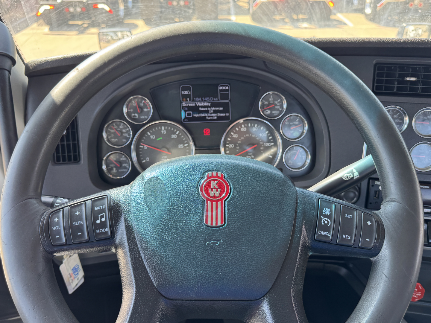 Kenworth T680 steering wheel and dashboard showing gauges and controls.