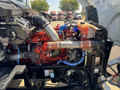 Kenworth T680 engine bay showing turbo manifold, hoses, coolant reservoir, and various engine components.