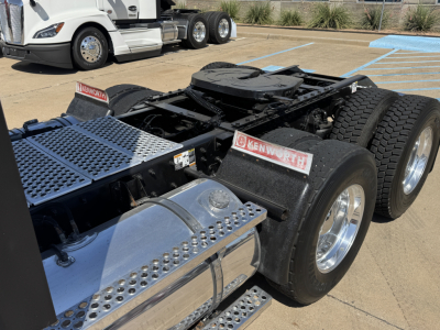 Kenworth T680 tractor rear chassis showing dual rear axles and chrome fuel tanks with perforated steps and Kenworth badges