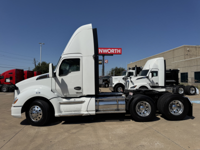 Kenworth T680 tractor in white, side view, with sleeper cab and dual rear axles on a dealership lot.