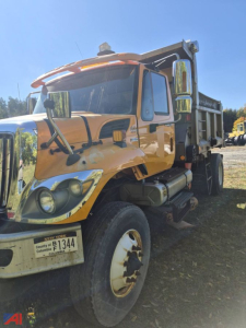 Dump truck with orange cab and white wheel rims; visible text includes New York license plate and COA F1344? on plate; side mirrors; dump bed; VIN not visible in image.