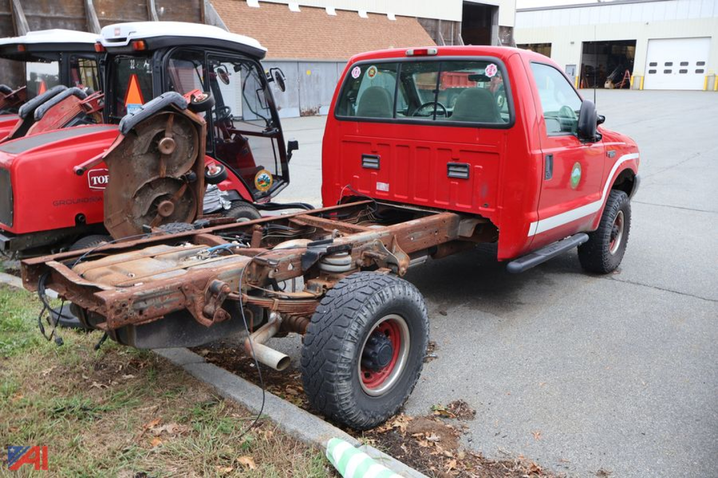 Ford F-350 Super Duty cab and chassis showing exposed chassis frame and rear axle, red pickup cab, old front suspension, in a lot.