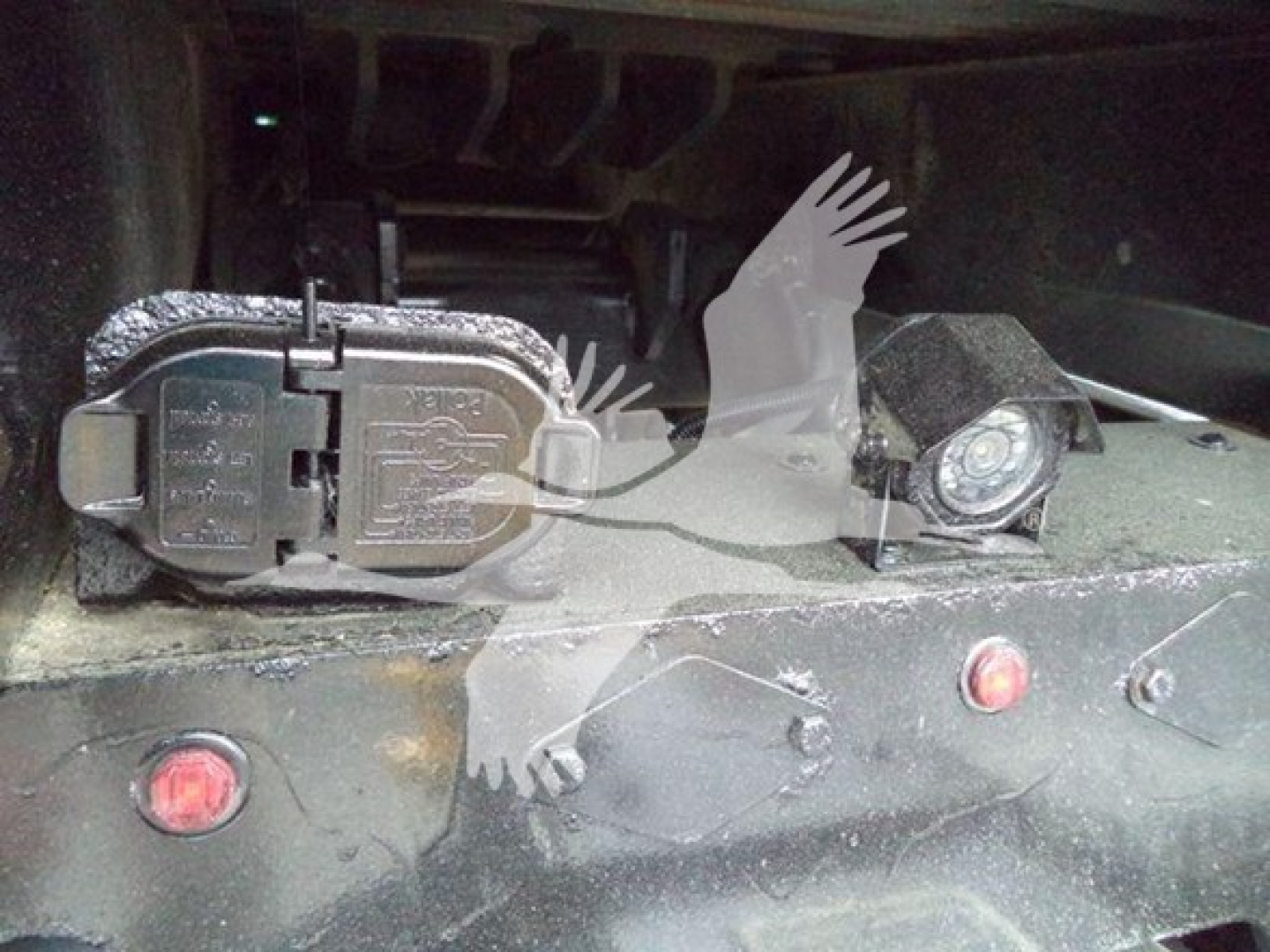 Rear-view of Peterbilt 348 roll-back chassis showing two electrical connectors and a round cap, with plastic label covers and red marker lights.