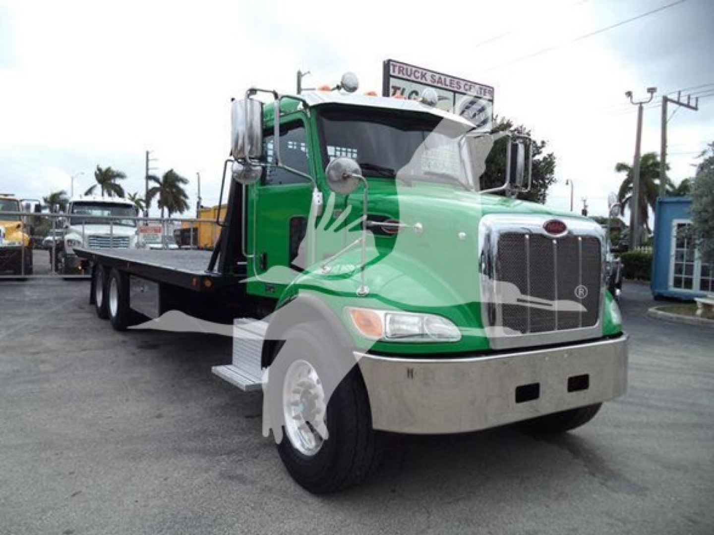 Peterbilt 348 rollback truck in green and black with flatbed and chrome front grille, side mirrors, and dual rear wheels.