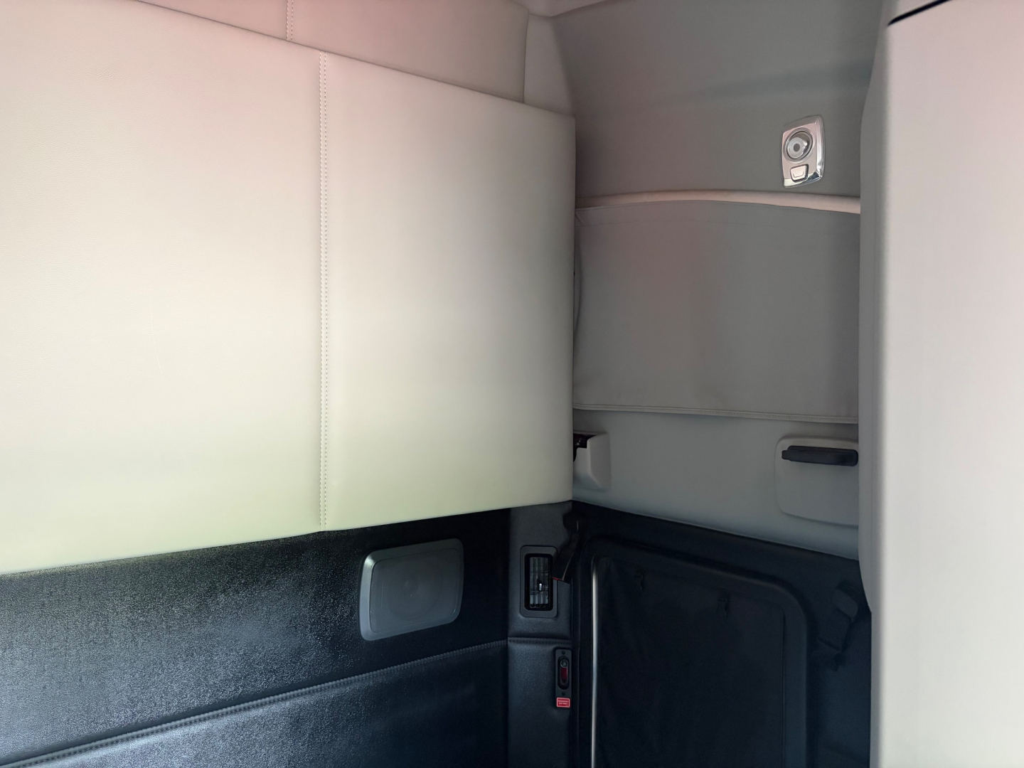 Kenworth T680 cab interior view with light-gray upholstery and storage cubbies.