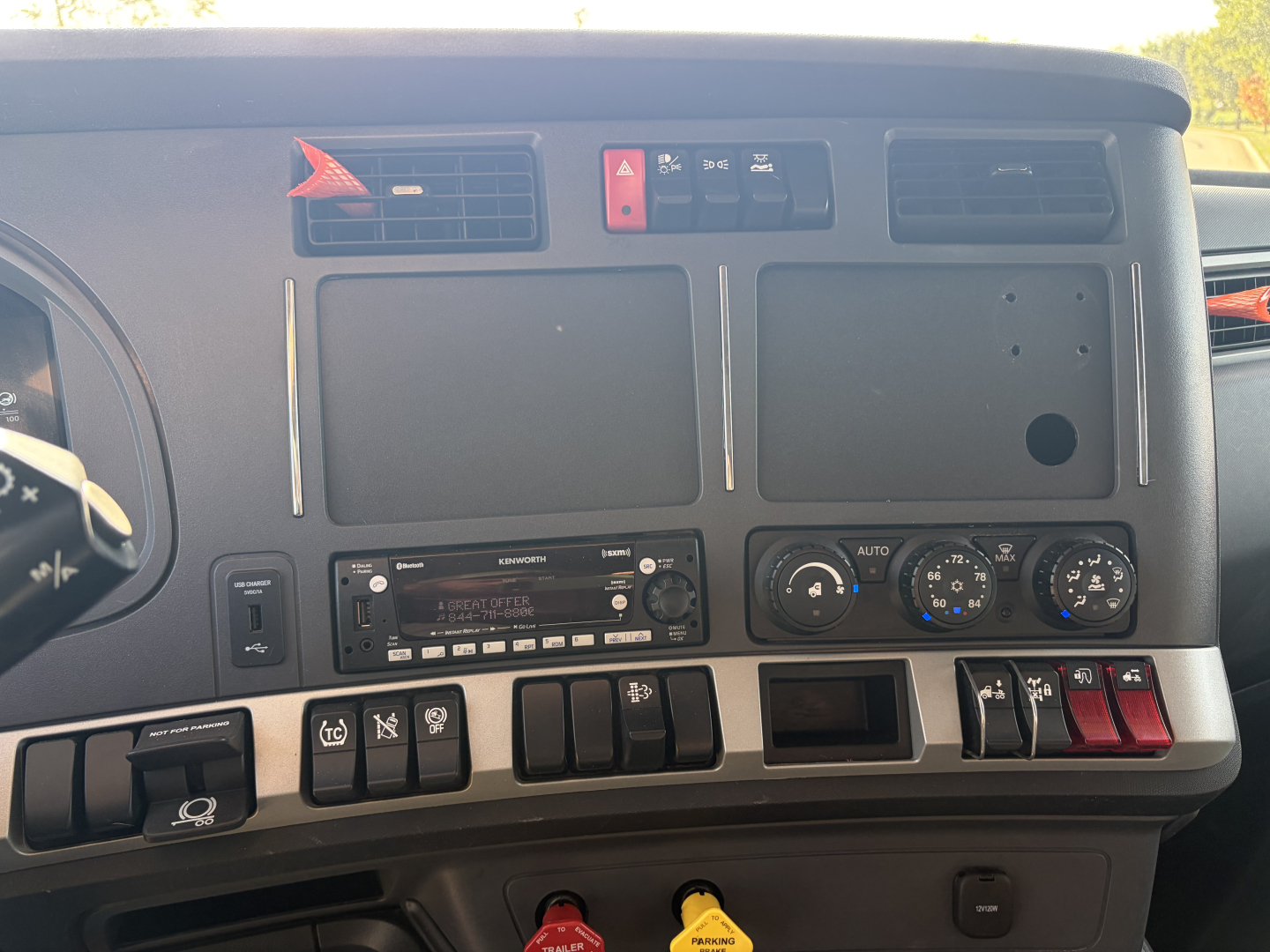 Kenworth T680 dash and center console with control switches, gauges, stereo, and climate controls visible; no specific text legible besides vehicle info sticker