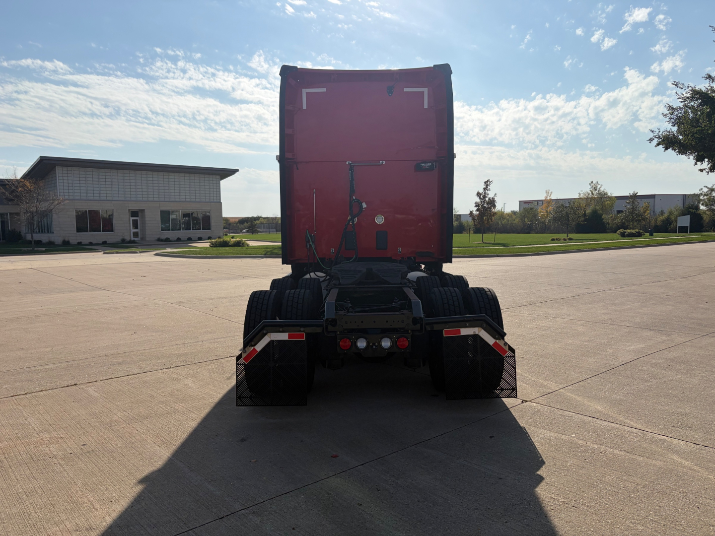 Kenworth T680 truck rear view showing fifth wheel, dual rear axles, and red sleeper cab.
