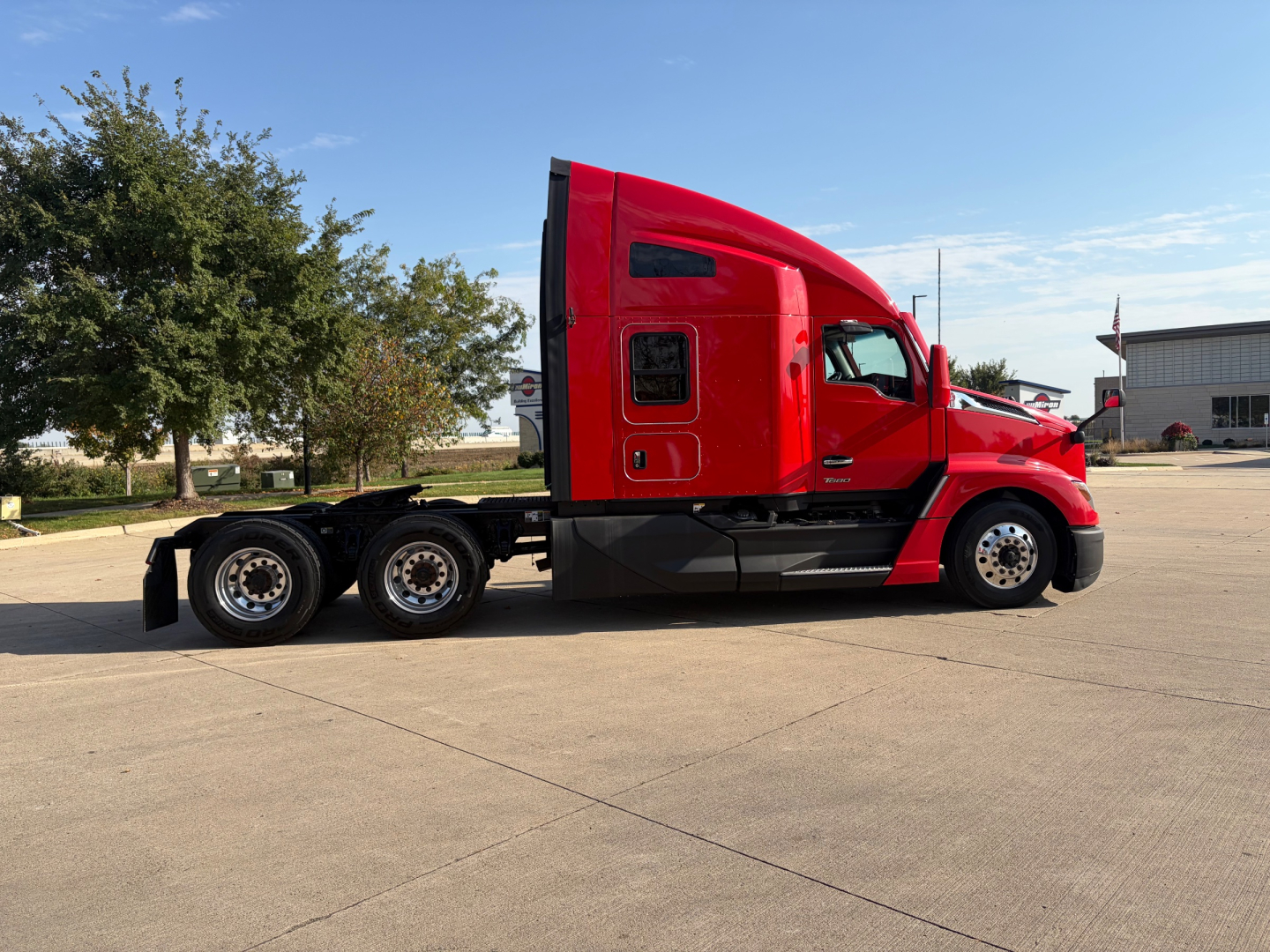 Kenworth T680 tractor in red, side view showing sleeper cab and multiple rear axles.