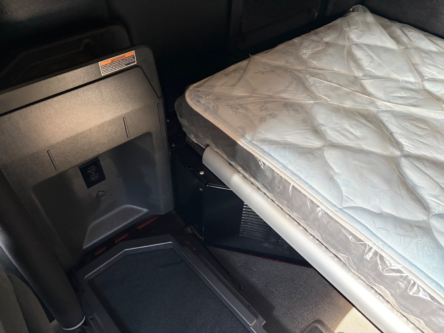 Kenworth T680 sleeper cab interior showing a folded bed mattress in the sleeper area and front dash panel with storage tray