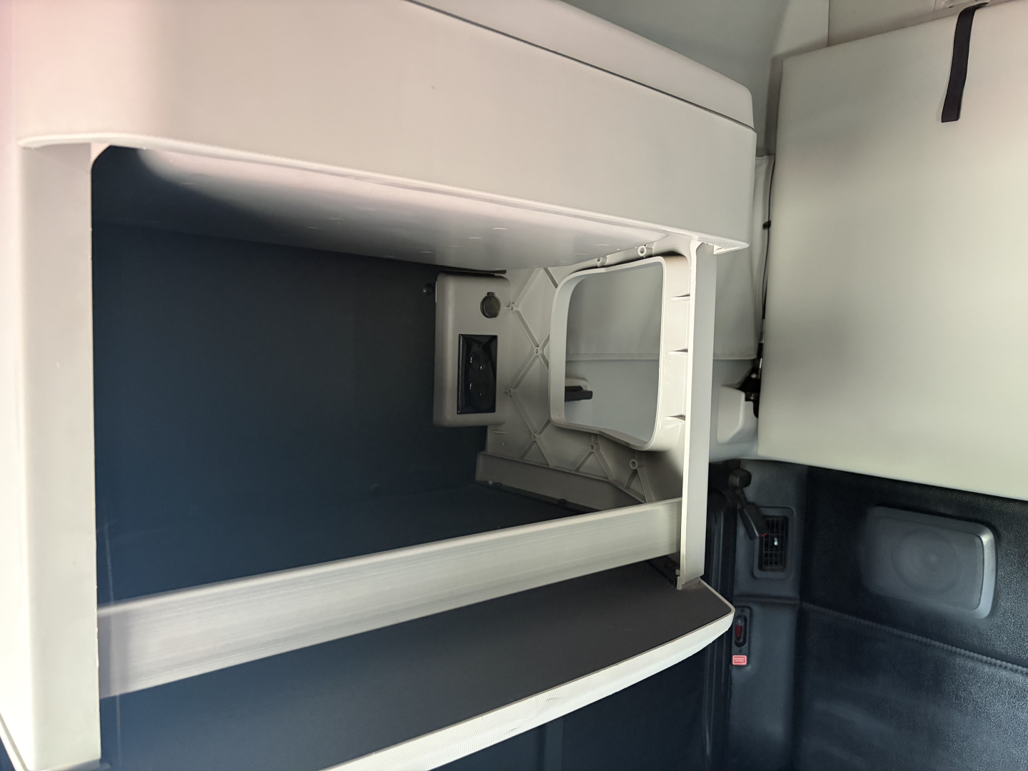 Kenworth truck cab interior showing open storage compartment and dashboard area.
