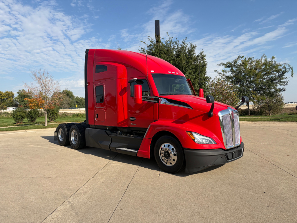 Kenworth T680 tractor with red cab, side view showing dual rear axles and front grille.