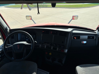 Kenworth T680 cabin/dash view from driver seat showing steering wheel, dashboard, center console, and front windshield with mirrors.