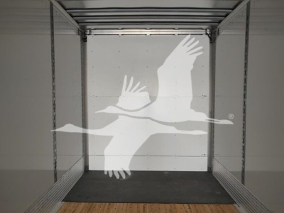 Van trailer interior showing empty cargo space with metal side rails and wooden floor at the rear doorway.