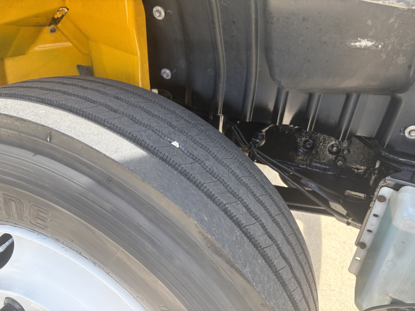 Truck wheel and suspension area showing tire treads and undercarriage components of a 2021 International MV607.