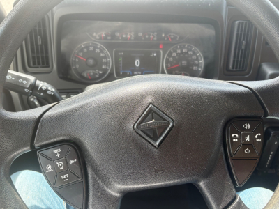Dashboard view of a 2021 International MV607 with steering wheel, instrument cluster, and center digital display showing zero mph, steering wheel emblem visible.