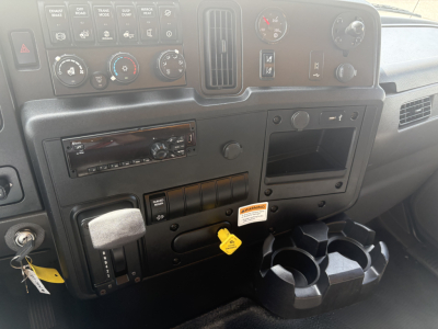 Dashboard and center console of a 2021 International MV607 commercial truck showing gauges, climate controls, radio, ignition, and cup holder attachments.