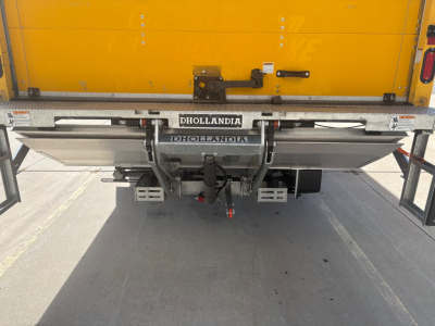 Rear view of a 2021 International MV607 truck with a Dhollandia tail lift and yellow cargo body, showing mounting hardware and dual hydraulic arms.