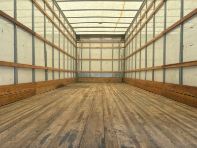 Trailer interior cargo area with wooden floor and metal walls, empty and well-lit.