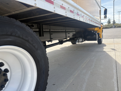 Truck undercarriage showing suspension and drive line with rear wheels and underbody of a box truck.