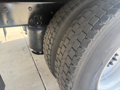 Truck wheel and undercarriage with air reservoir and dual rear tires visible in a box truck chassis.
