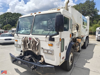 White Peterbilt 320 automatic garbage truck in a lot, front view showing grabber arms on the front bumper and refuse body with side mirrors and ladders.