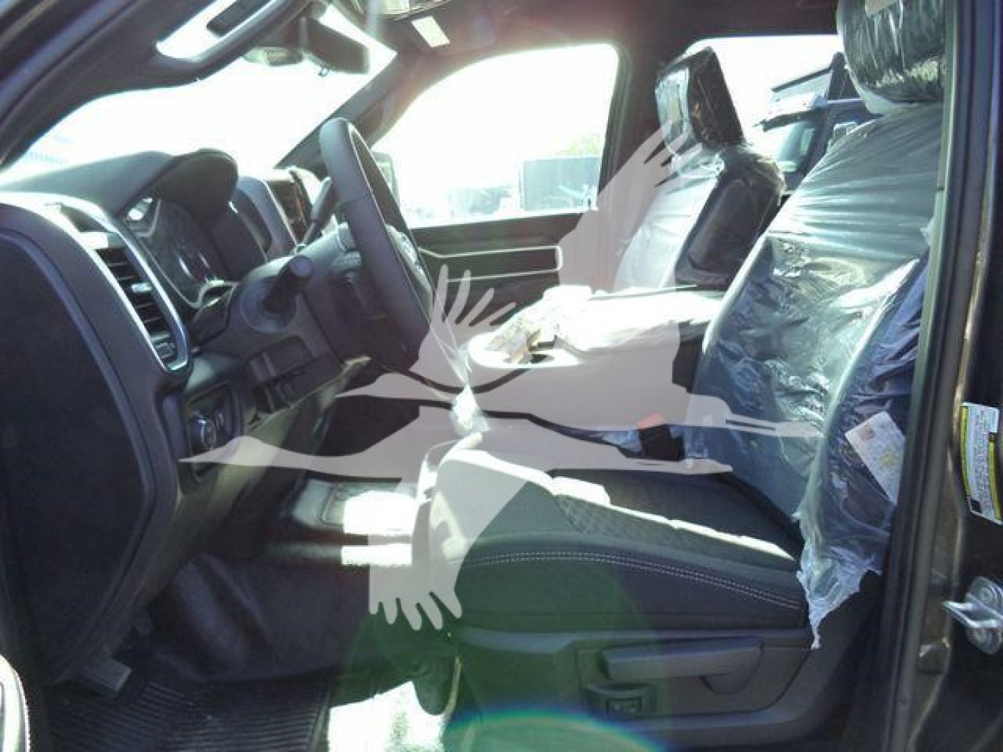 Ram 5500 Big Horn interior view showing front seats and steering wheel, plastic seat covers on passenger seat, dashboard and center console visible.