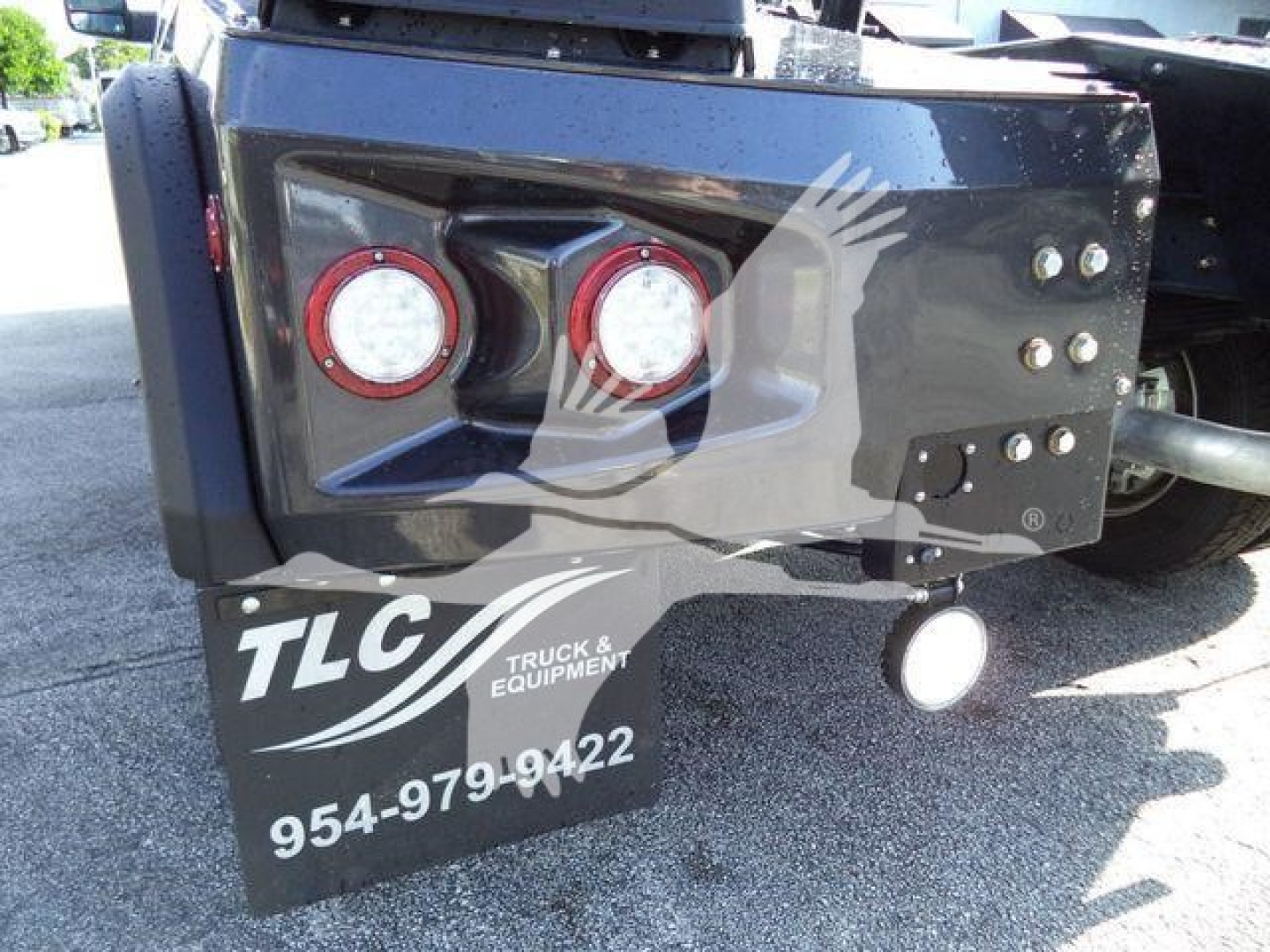 Truck bed rear showing two red round taillights, black toolbox with TLC Truck & Equipment logo, and contact number 954-979-9422.