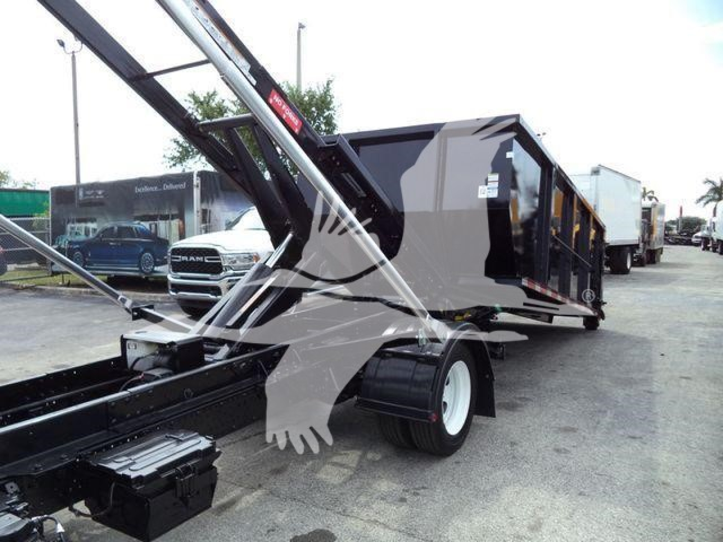 2017 Isuzu NPRR roll-off truck with hydraulic arm and gray/dark gray dump body; side view shows wheels and front hitch area.