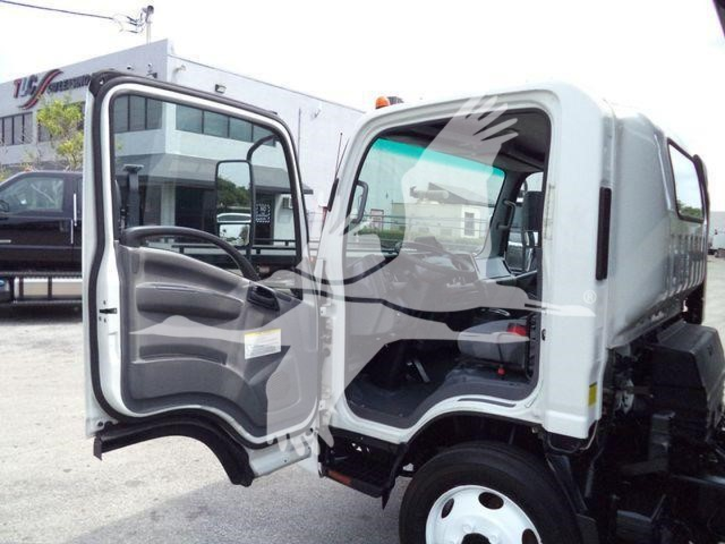 Isuzu NPR/NRR truck cab with driver door open, showing interior dashboard and steering wheel, white exterior, roll-off body in background.
