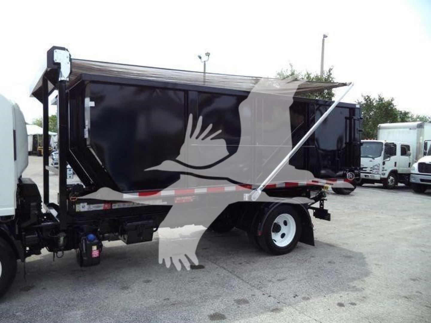 Isuzu NPR rolloff truck side view showing dumped cargo bed and rear wheels