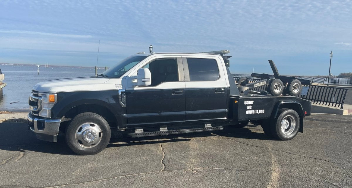 Ford Super Duty F-350 DRW tow truck side view showing flatbed with equipment and branding.