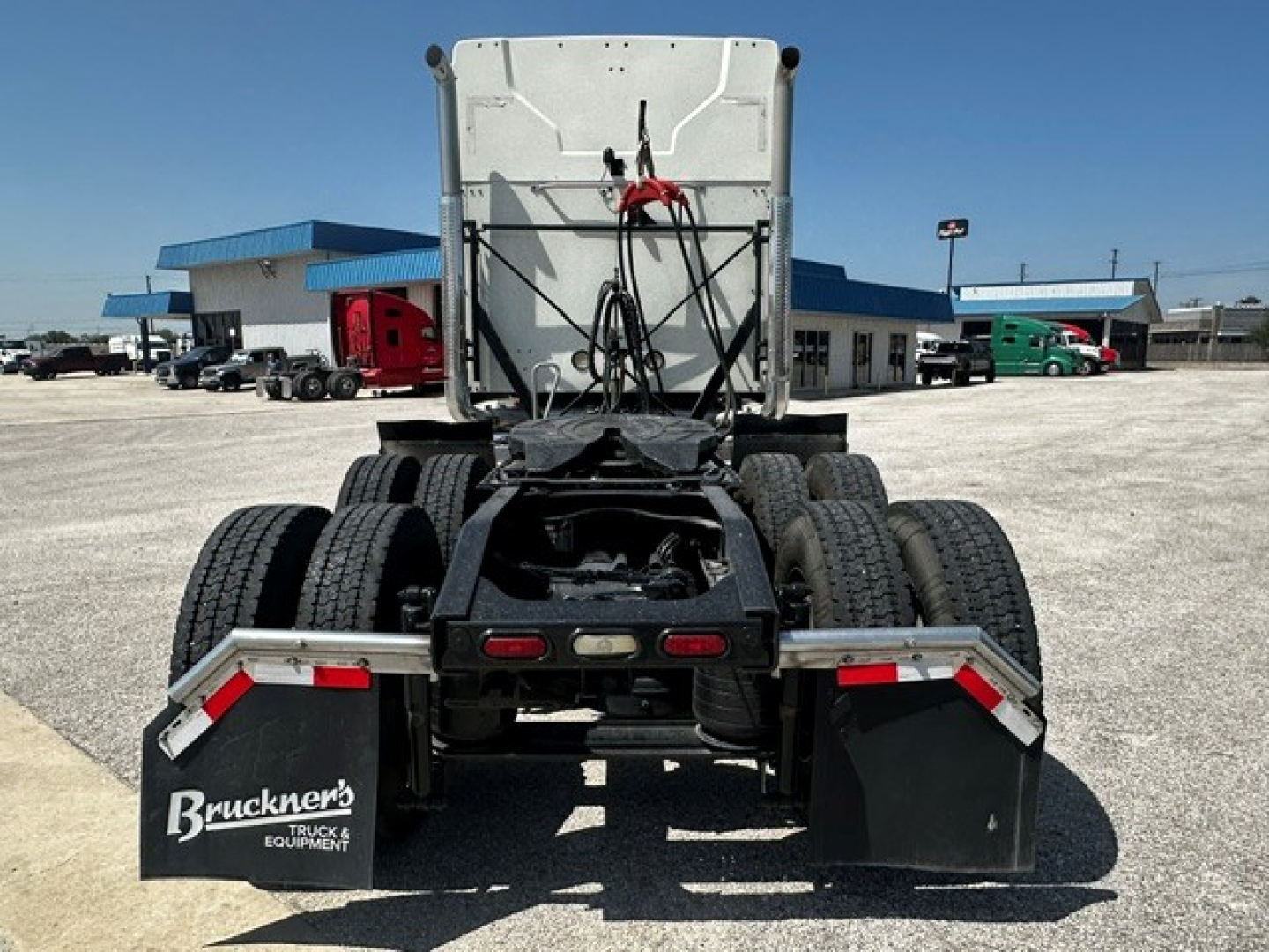 Truck chassis rear view showing dual rear axles and mud flaps with Bruckner's Truck Equipment logo, fifth wheel and wiring harness visible in a used 2020 Mack Anthem.
