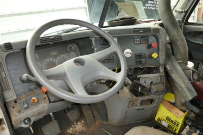  Freightliner CL112 dash area showing steering wheel, dashboard gauges, and control switches in a used daycab interior.