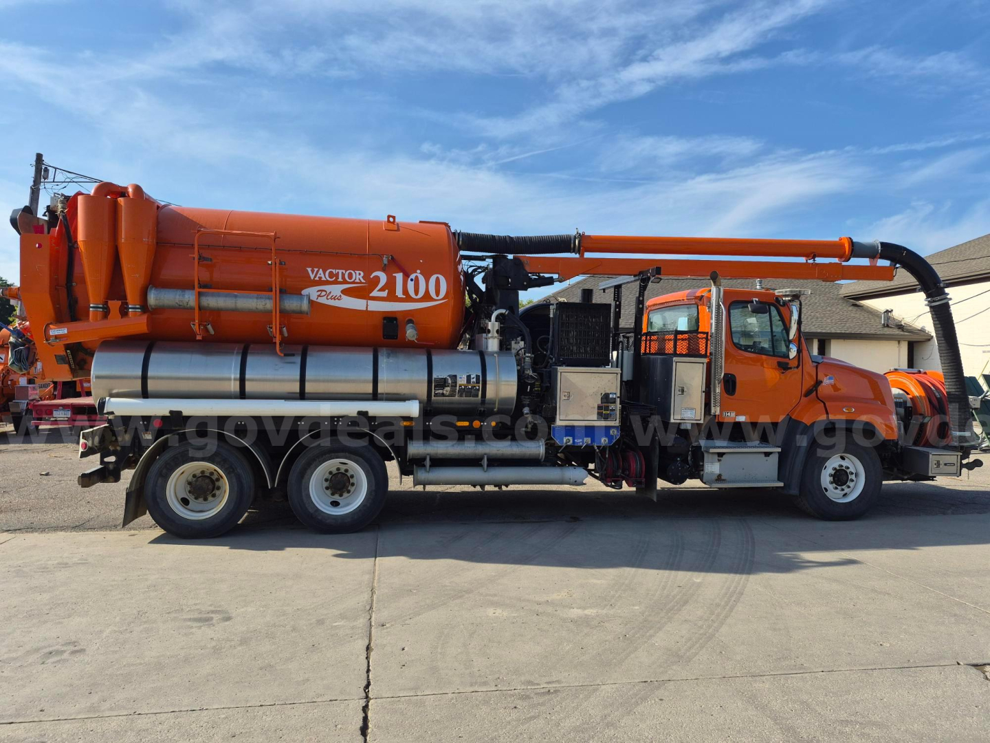 Freightliner vacuum truck with orange Vactor 2100 hose system on a large chassis, side view showing tank, hoses, and cab; 2017 Freightliner 114SD.