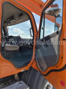Freightliner cab interior with orange exterior showing dashboard and open door.