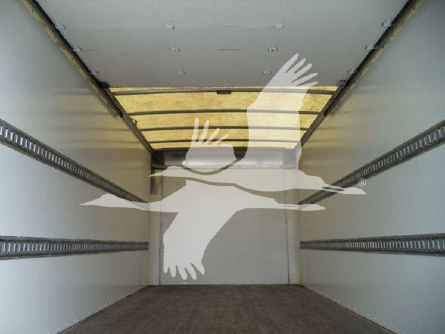 Interior of a box truck cargo area with side rails and a wooden floor, seen from the back toward the cab.