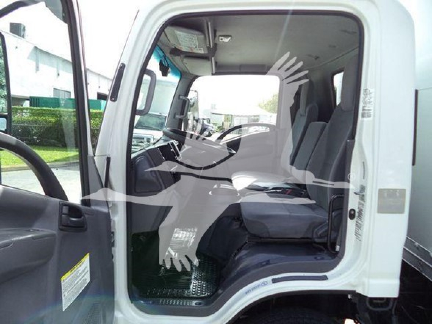 Isuzu NPR HD truck cab interior view from open driver door showing steering wheel and seating area.