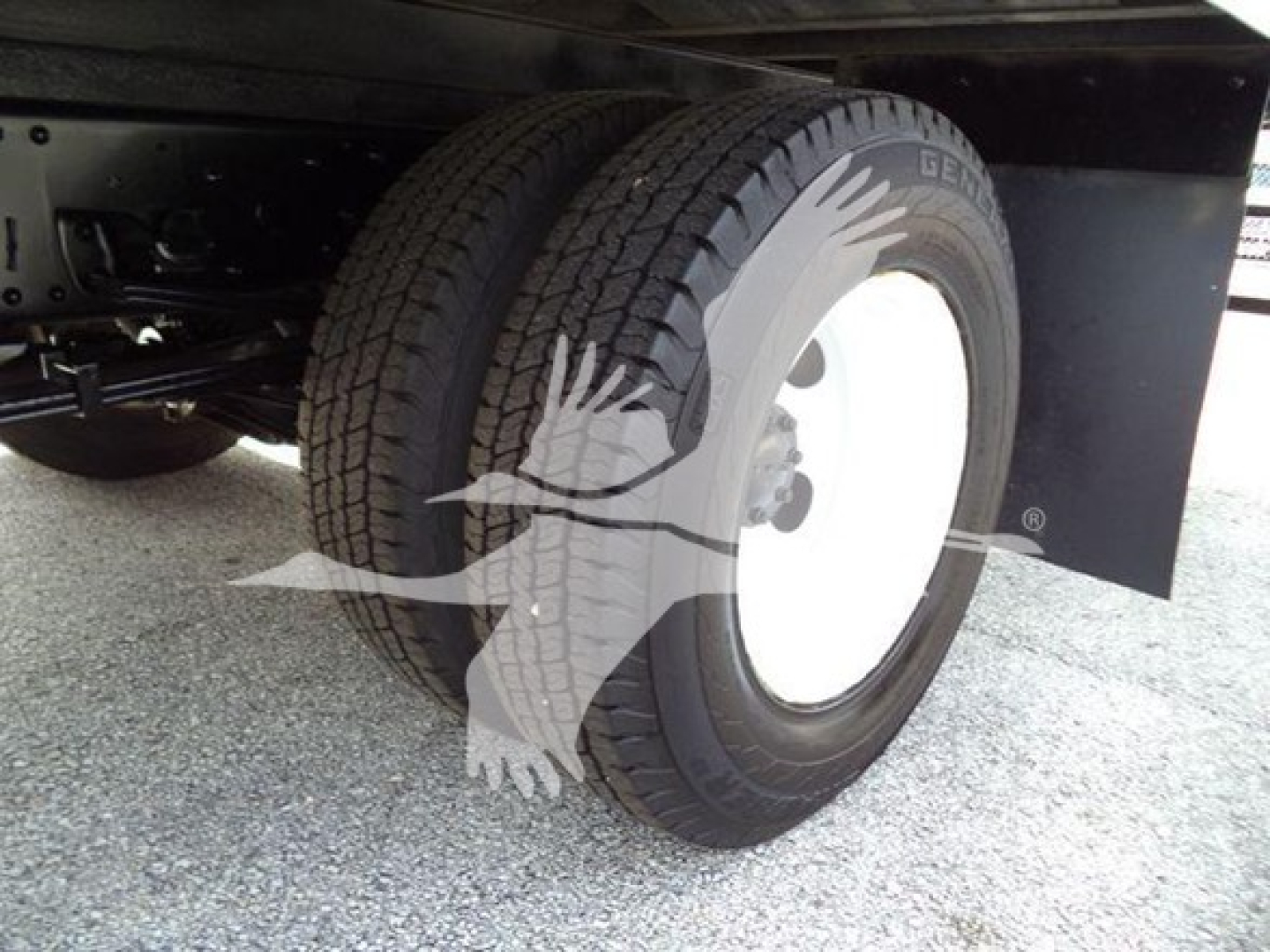 Isuzu NPR HD truck wheel and rear tire with white steel rim and black fender; visible tread and undercarriage components.
