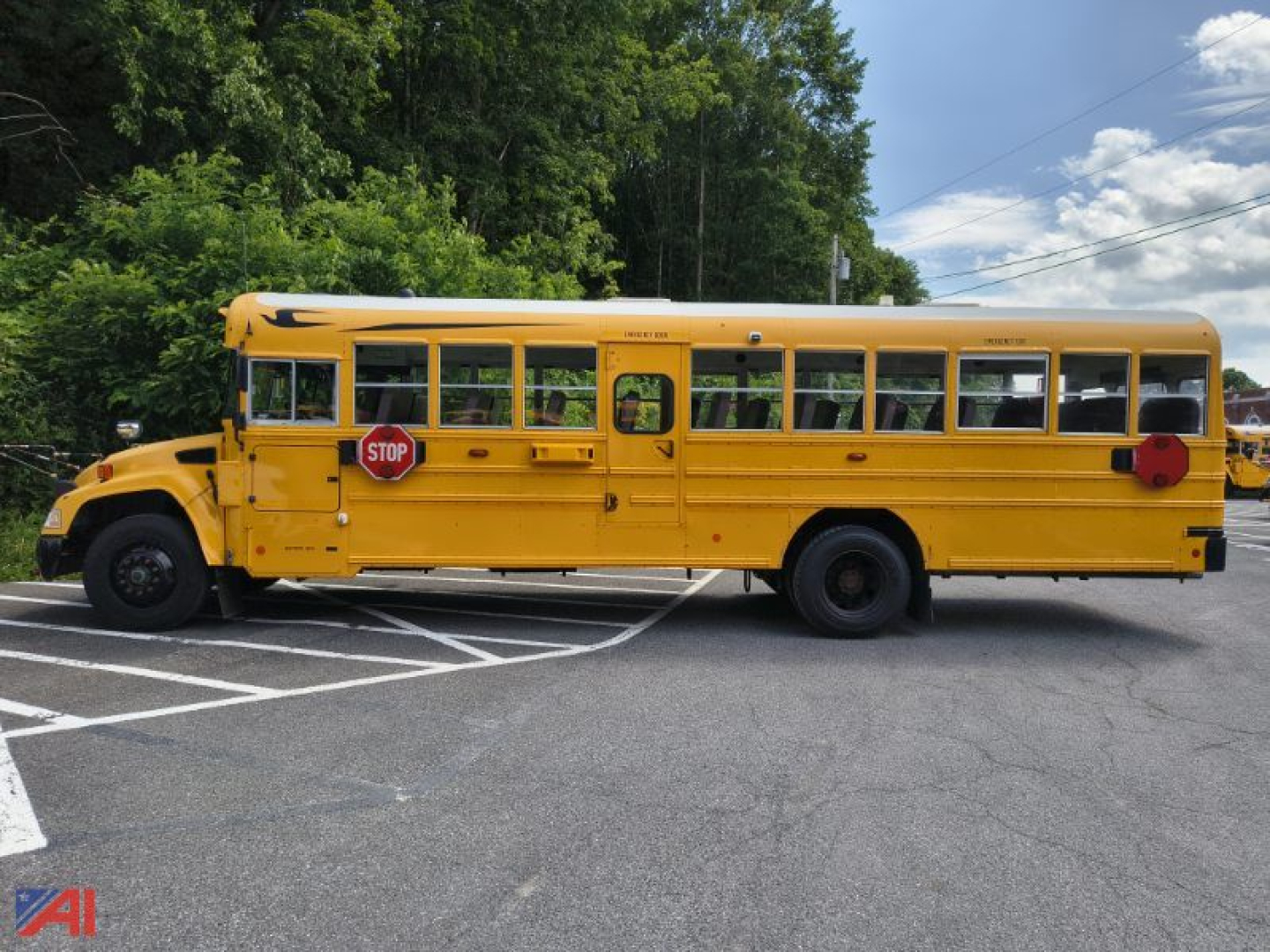 School bus side view showing a yellow 2016 Blue Bird Vision with STOP sign extended and school bus lettering, side doors, windows, and wheel wells.