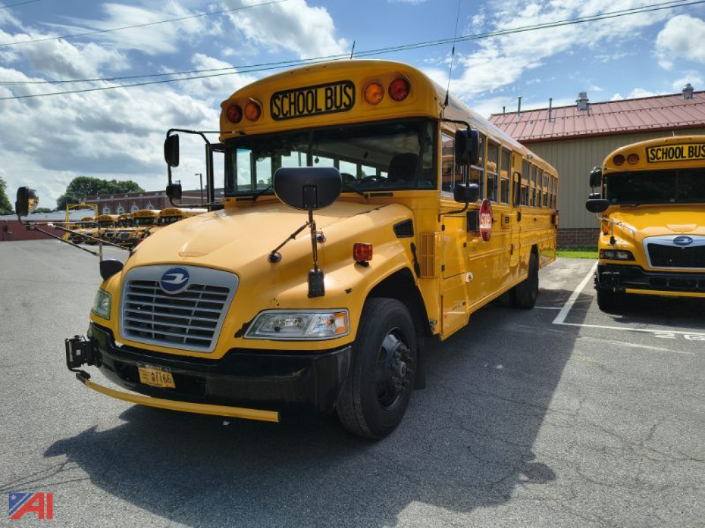 Yellow 2016 Blue Bird Vision school bus parked with mirror extending, front grille, and side emergency exit visible.