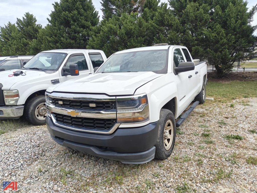White 2017 Chevrolet Silverado 1500 Crew Cab pickup truck front-left view in a gravel lot with other vehicles and trees in background.