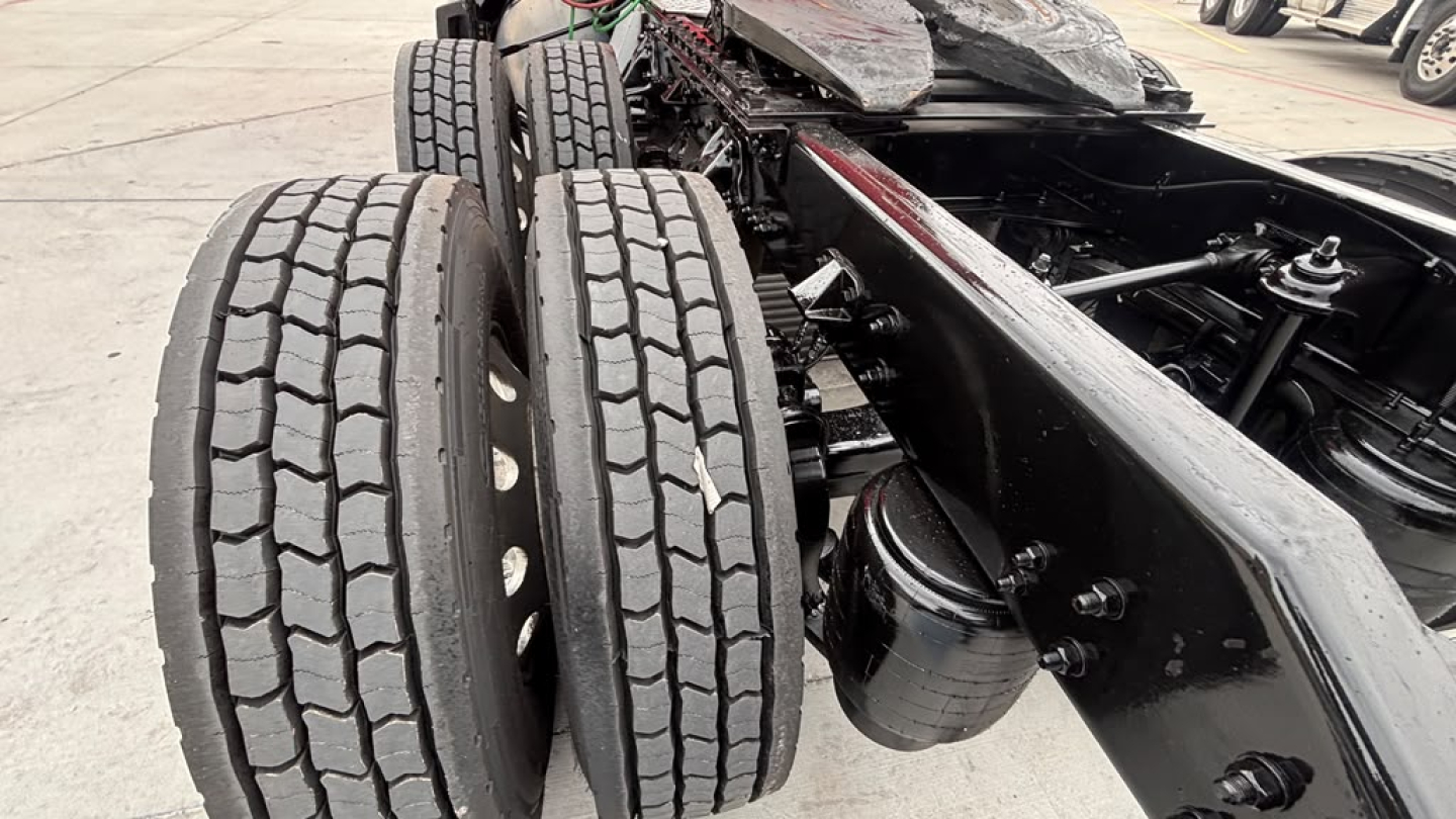 Kenworth T680 chassis view showing dual rear axles with tires and frame rails; emphasis on wheel hubs and suspension components.