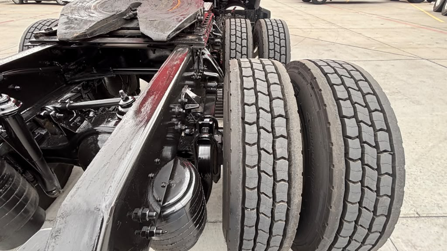 Kenworth T680 chassis showing dual rear axles and tire tread close-up, with visible drivetrain and frame components.