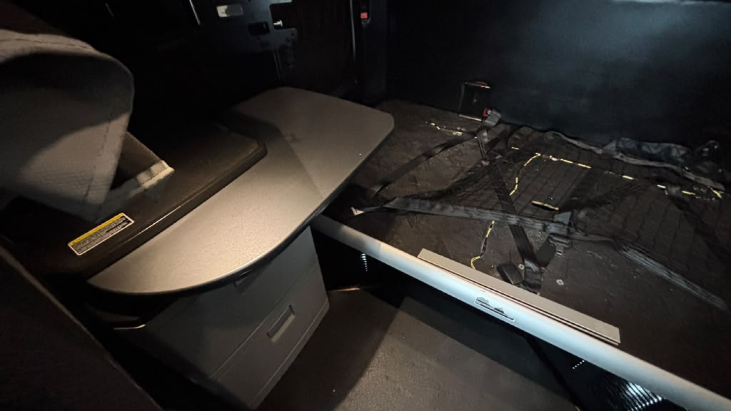 Kenworth T680 interior cargo area with seating and folded bunk area; visible straps and floor paneling.